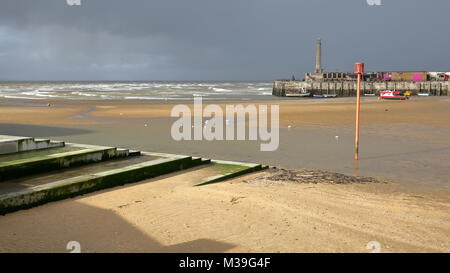 La plage à marée basse par temps venteux et orageux avec bras de port de Margate dans l'arrière-plan, Margate, Kent, UK Banque D'Images