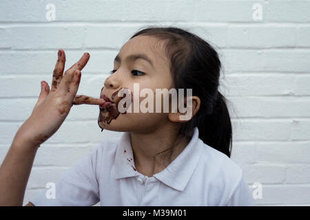 Enfant de manger du chocolat avec désordre sur face Banque D'Images