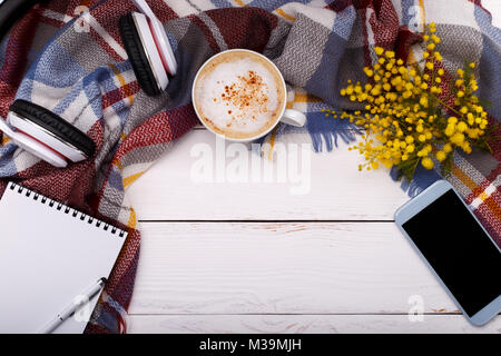 Un café chaud, cappucino, couverture,mimosa ,notepad,smartphone et un casque sur l'ancien fond de bois. Vous pourrez vous détendre saison,concept mise à plat Banque D'Images