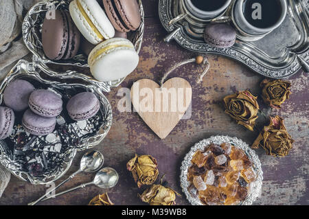 Des petits macarons sur une plaque de métal avec des petites fleurs et un coeur en bois . Focus sélectif. Close up. Banque D'Images