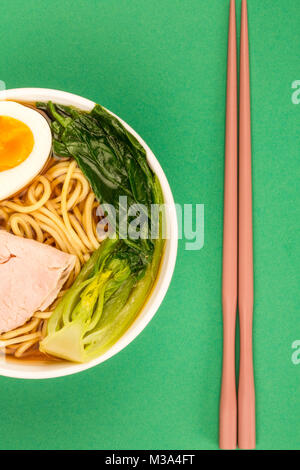 Bol de nouilles ramen de porc style Japonais soupe avec Pak choi et un Œuf dur sur un fond vert Banque D'Images