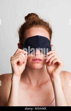 Parution du modèle. Jeune femme fatiguée portant un masque de sommeil couvrant ses yeux. Banque D'Images