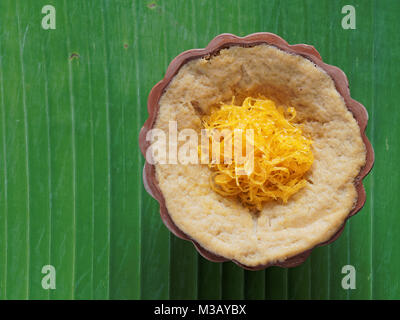 Dessert thaï, crème d'oeufs avec le riz gluant sucré surmonté de fils d'or, sur fond de feuilles de banane Banque D'Images