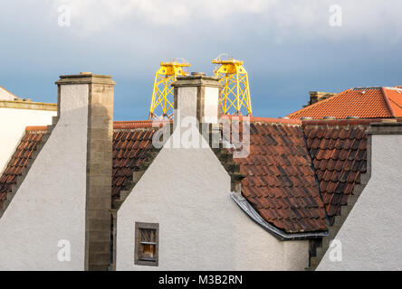 Leith, Édimbourg, Écosse, Royaume-Uni. Juxtaposition incongrue d'immenses plates-formes éoliennes ensoleillée jaune, appelé windfarm vestes, en dominant le port de Leith pantile toit de l'un des bâtiments les plus anciens de Leith, 17e siècle Lamb's House, une ancienne maison de marchands hanséatiques Leith, maintenant à la maison à l'architecte qui l'a restaurée, Nicholas Groves Raines. Ces plates-formes d'arriver à Leith en route vers le nord pour fournir une sous-structure de turbines dans un parc éolien offshore dans le Moray Firth Banque D'Images