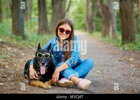 Jeune fille avec un chien en lunettes de soleil dans le parc. Berger allemand Banque D'Images