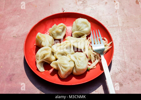 Plaque rouge de l'alimentation traditionnelle népalaise. momos Cuit vapeur avec salade momos à Gangtok, Inde Banque D'Images