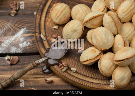 Les écrous en forme de cookies faits maison avec de la crème de lait concentré bouilli sur table en bois. Style rustique dans le contexte des ingrédients Banque D'Images