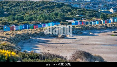 MORAY HOPEMAN SCOTLAND LONGUE RANGÉE DE CABINES DE PLAGE DE COULEUR EN DESSOUS DU VILLAGE DE MAISONS DANS WINTER SUNSHINE Banque D'Images