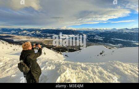 INNSBRUCK, Autriche - 26 janvier : (NOTE DU RÉDACTEUR : la latitude d'exposition de cette image a été numériquement augmenté.) Un touriste prend une photo de la ville et les Alpes au Mont Seegrube le 26 janvier 2018 à Innsbruck, en Autriche. Banque D'Images