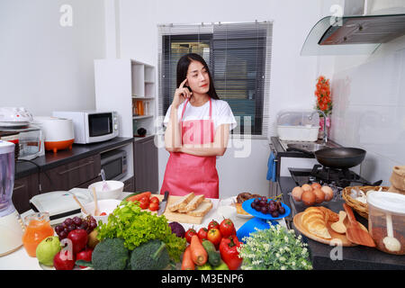 Femme de penser à la cuisson dans la cuisine chambre à la maison Banque D'Images