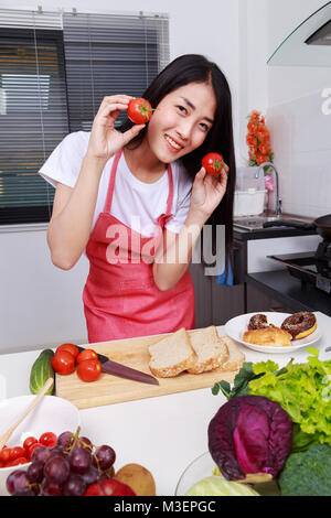 Woman holding tomato dans la cuisine chambre à la maison Banque D'Images