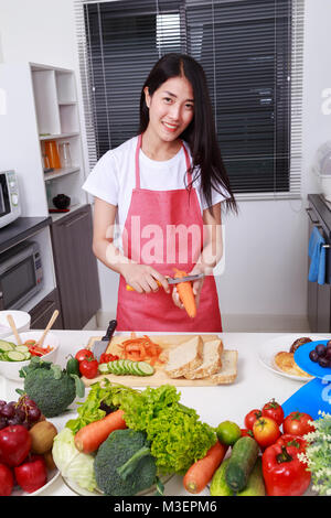 Peler les carottes femme avec un couteau dans la cuisine prix Banque D'Images