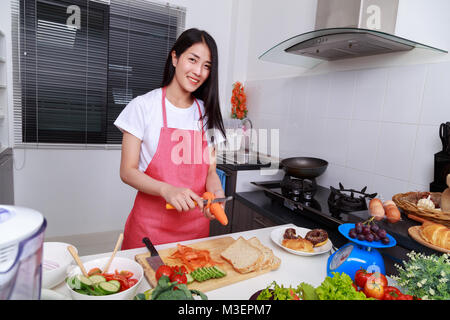 Peler les carottes femme avec un couteau dans la cuisine prix Banque D'Images