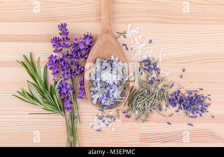 Vue de dessus avec une cuillère de sel aux herbes de romarin et lavande fleurs sur un fond de bois Banque D'Images