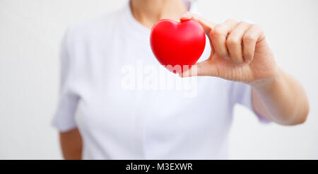 Focus sélectif de cœur rouge tenu par une infirmière, représentant la main de donner à tous les efforts possibles pour offrir des services de haute qualité à l'esprit du patient. Professional Banque D'Images