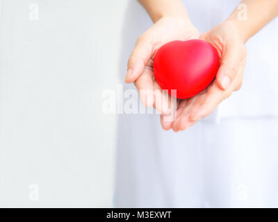 Focus sélectif de cœur rouge tenue par une infirmière est à la fois la main, représentant donnant à tous les efforts possibles pour offrir des services de haute qualité à l'esprit du patient. Professer Banque D'Images