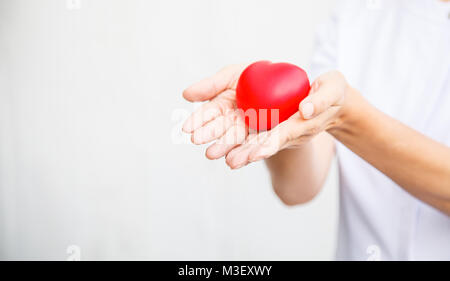 Focus sélectif de cœur rouge tenue par une infirmière est à la fois la main, représentant donnant à tous les efforts possibles pour offrir des services de haute qualité à l'esprit du patient. Professer Banque D'Images