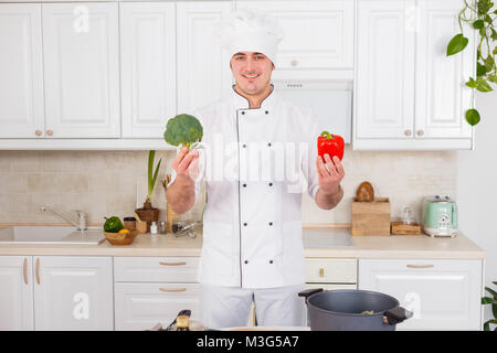 Chef professionnel choisit entre le poivron rouge et le brocoli. Banque D'Images