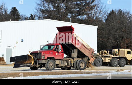 Un opérateur de l'équipement avec le Fort McCoy entrepreneur en déneigement, Kaiyuh Services LLC d'Anchorage, Alaska, les lieux du sable sur une surface glacée, le 30 janvier 2018, à Fort McCoy, au Wisconsin (É.-U. Army Banque D'Images