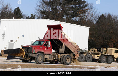 Un opérateur de l'équipement avec le Fort McCoy entrepreneur en déneigement, Kaiyuh Services LLC d'Anchorage, Alaska, les lieux du sable sur une surface glacée, le 30 janvier 2018, à Fort McCoy, au Wisconsin (É.-U. Army Banque D'Images