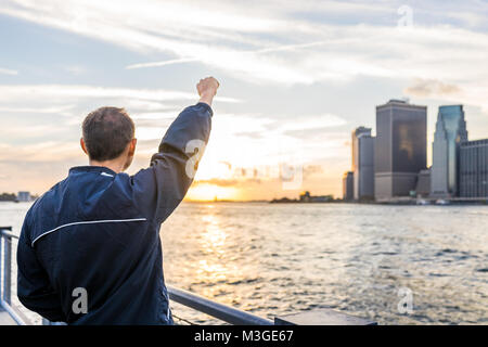 Dos de jeune homme à l'extérieur extérieur dans NYC New York City Pont de Brooklyn Park par East River, garde-corps, à la vue des toits de la ville au coucher du soleil, stat Banque D'Images