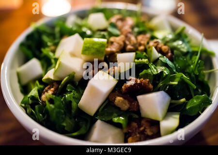 Gros plan macro de roquette salade végétarien végétalien vert pomme en restaurant avec noix confites, noix, sur table en bois en soirée dîner Banque D'Images