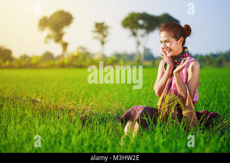 Happy Farmer woman sitting in riz vert déposé, Thaïlande Banque D'Images