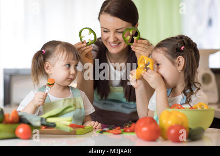 Famille heureuse maman et les enfants s'amuser avec la nourriture des légumes au poivre cuisine détient devant leurs yeux comme dans les verres Banque D'Images