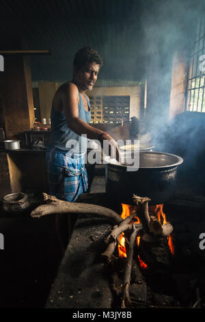 Un homme dans la cuisine la cuisine d'un petit restaurant en bordure de route, dans le Tamil Nadu. Banque D'Images