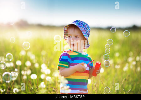 Bébé garçon debout dans l'herbe sur le fieald de pissenlits Banque D'Images