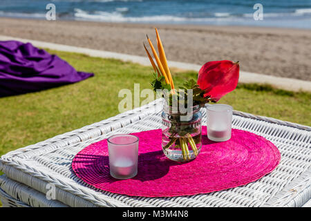 Configuration du parti coloré près de l'océan, de tables, de bougies et de bouquets de fleurs, Bali, Indonésie Banque D'Images