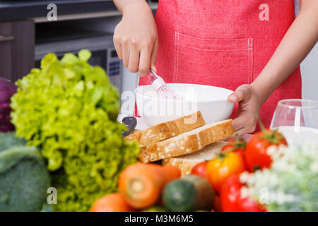 Close up of hand et la cuisson en fouettant les oeufs dans un bol dans la cuisine chambre à la maison Banque D'Images