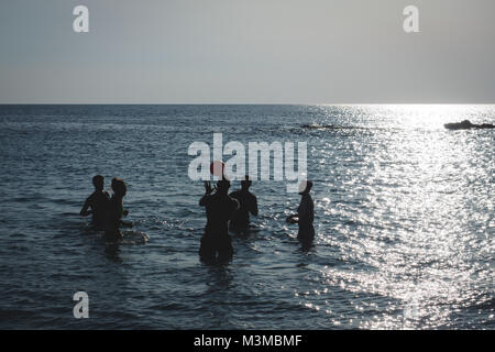 Gallipoli (Italie), août 2017. Un groupe de jeunes gens jouer au volley-ball dans la mer au coucher du soleil sur la plage de Padula Bianca. Le format paysage. Banque D'Images