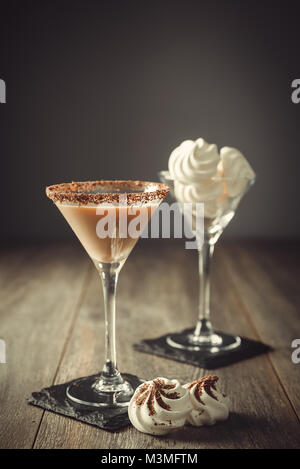 Boisson à la crème irlandaise en verre avec rim enrobées de chocolat et un verre de mini meringues à l'arrière-plan Banque D'Images