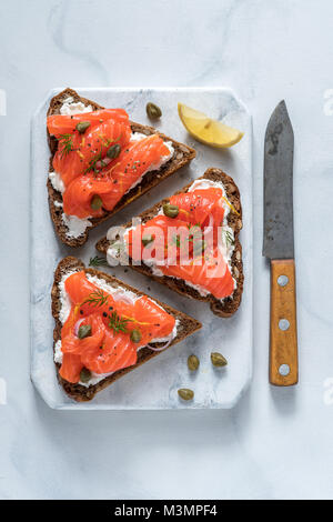 Smorrebrod danois traditionnel, ouvrez sanwiches, pain de seigle foncé avec du saumon, du fromage à la crème et les câpres. Vue d'en haut. Banque D'Images