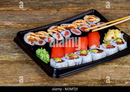 Ensemble d'un assortiment de sushi servi dans une boîte en plastique sur la table en bois Banque D'Images