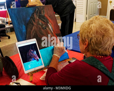 Les aînés ayant vécu une longue dure toujours demeurer actif s'exprimer en classe de peinture, Pam Smith utilise une photo prise avec son iPad pour peindre un cheval d'amis. Banque D'Images