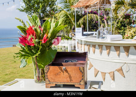 Comptoir de bar en plein air, carte en bois fort et d'un vase de fleurs tropicales. Configuration de mariage de plage près de l'océan. Banque D'Images