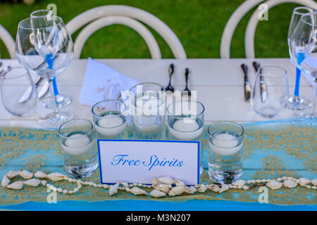 Set table soirée pour un livre blanc et bleu aqua beach dîner de mariage. Des bougies, des verres à vin, des obus et une carte d'esprits libres. Banque D'Images