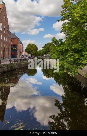 Ciel bleu avec des nuages blancs moelleux reflète dans regardez la surface d'un canal dans le centre-ville d'Uppsala, Suède Banque D'Images