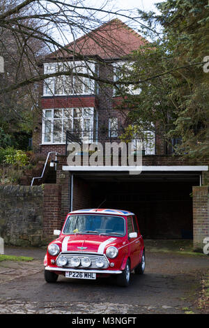 Un classique, voiture Mini Cooper rouge avec toit Union Jack et les grandes lampes de brouillard en face d'une chambre de luxe. Banque D'Images