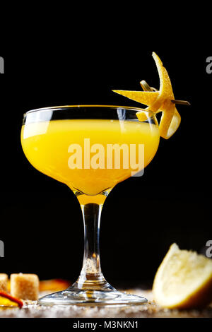 Verre à cocktail de citron jaune sur la barre, sur un fond noir. Le bar est décoré avec des zestes de citron Banque D'Images