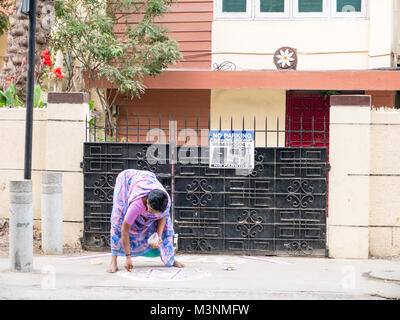 Chennai, Inde - Le 14 janvier 2018 : l'Inde Femme dessinant un Kolam (Rangoli) - forme de peinture tirée par l'utilisation de poudre de riz à l'avant de la maison - Banque D'Images