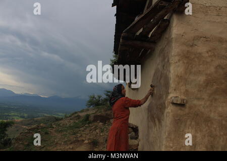 Femme du Cachemire l'application de la bouse de vache sur les murs, kupwara, Cachemire, Inde, Asie Banque D'Images