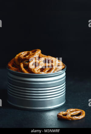 Bretzels croustillants apéritif dans un pot en métal sur un tableau noir. Lumière mystique style. Banque D'Images