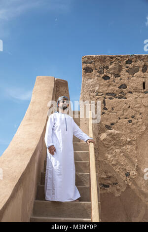 L'homme arabe en costume traditionnel omanais en descendant les escaliers Banque D'Images