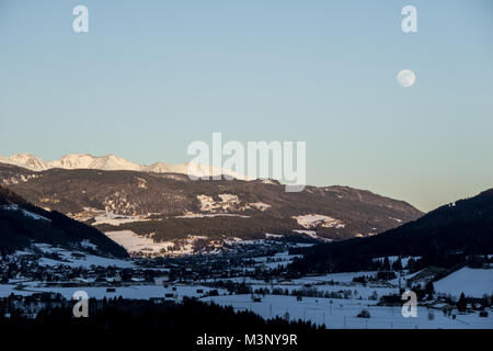 Une campagne magnifique paysage avec soleil sur les sommets des montagnes couvertes de neige dans la soirée et la Lune se levant au-dessus de la vallée Banque D'Images