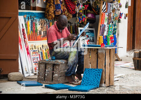 STONETOWN, Zanzibar - JAN 1, 2018 : l'artiste locale travaillant sur Tinga Tinga peinture colorée pour un magasin de souvenirs à Stone Town, Zanzibar Banque D'Images