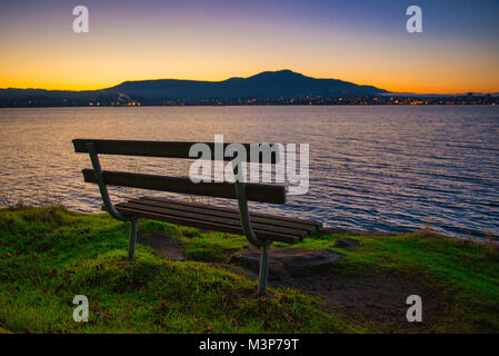 Vue du coucher de soleil d'un banc avec vue sur la baie de Nanaimo et skyline, prises de Jack Point et Biggs Park à Nanaimo, en Colombie-Britannique. Banque D'Images