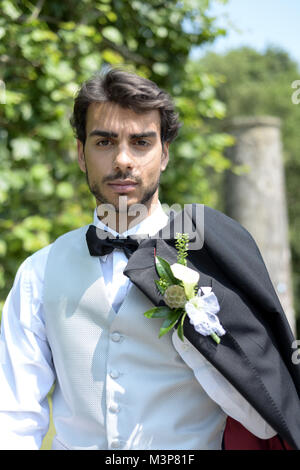 Portrait d'un beau jeune homme aux cheveux noirs en habit de noces sur une journée ensoleillée, il a l'air confiant et heureux Banque D'Images